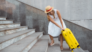 Woman pulling heavy luggage up stairs